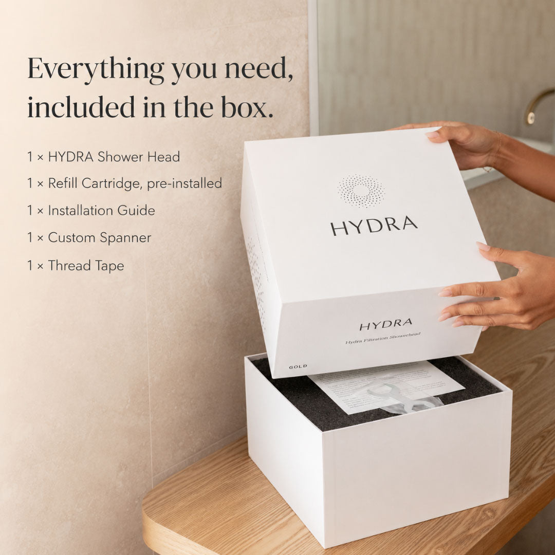 Person opening a Hydra filtered shower head box with product list on a bathroom shelf.